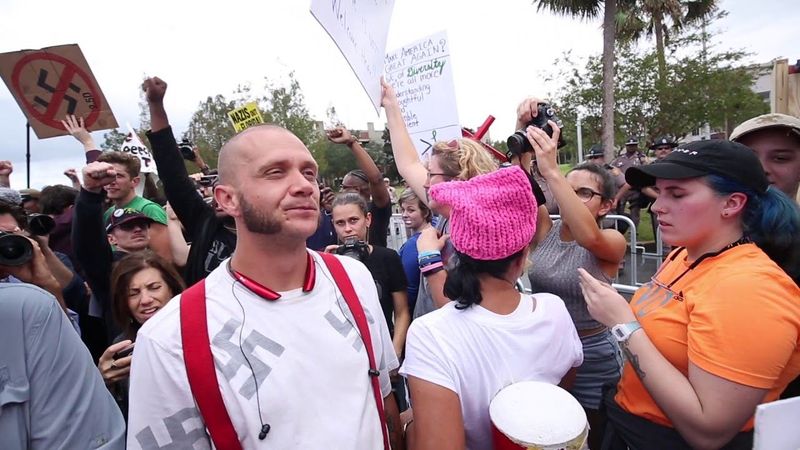 Swastika-wearer walks amid protesters, gets punched